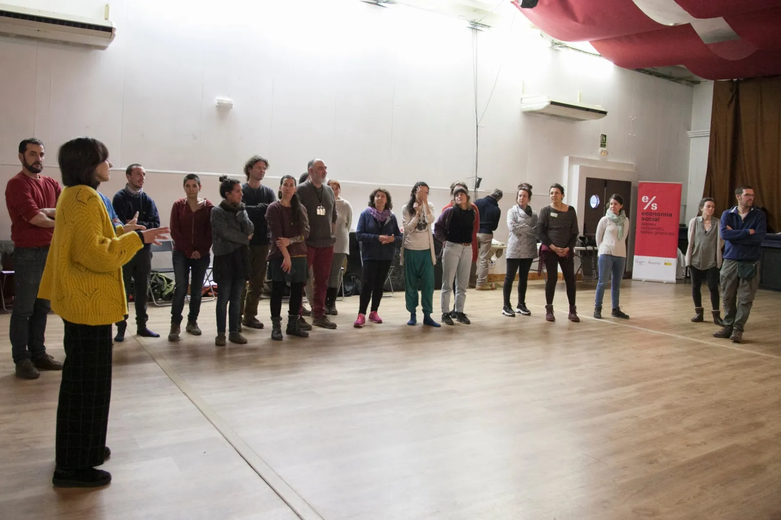 Participants drets en rotllana en una sala àmplia.