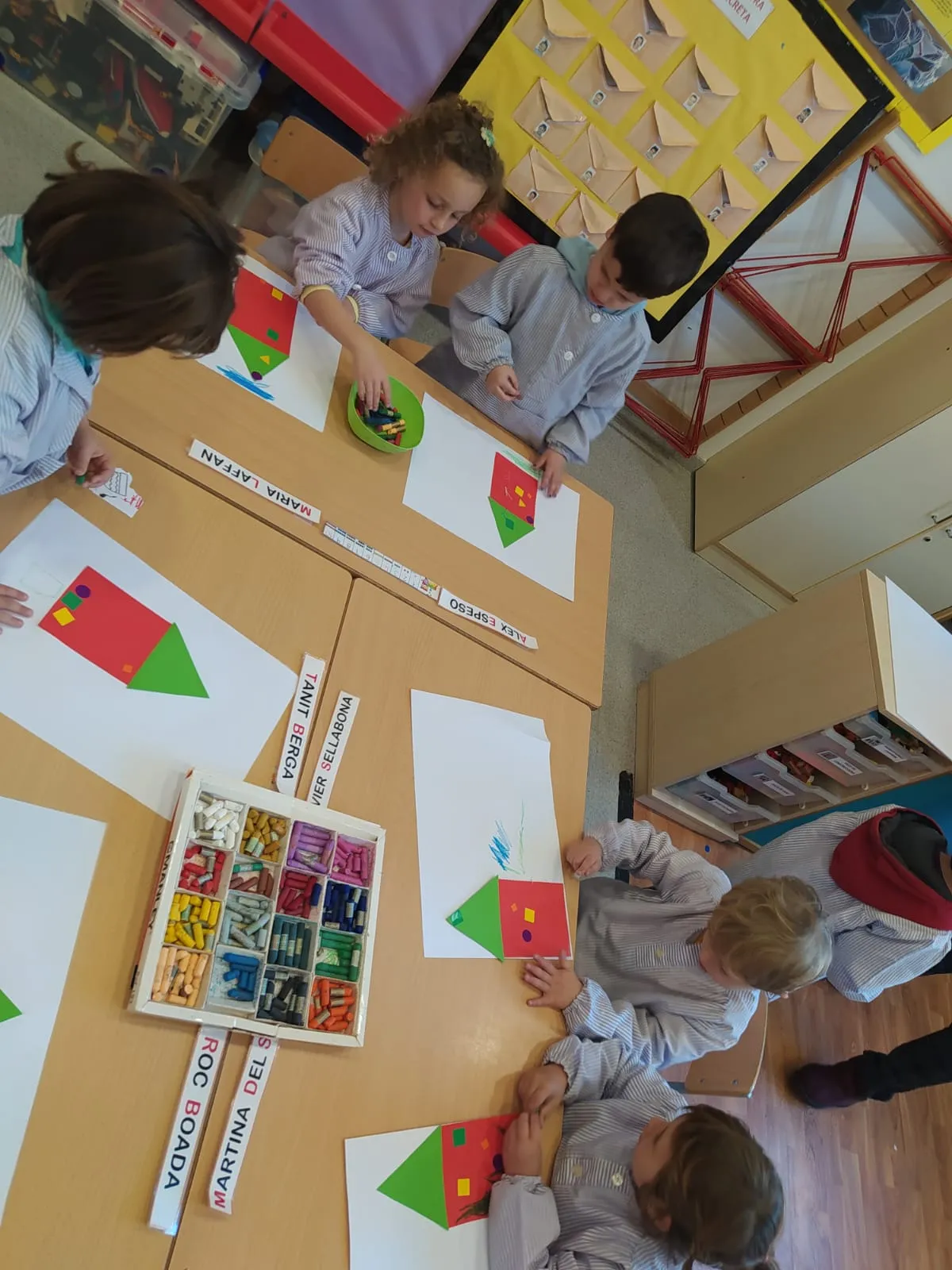 Infants de P4 i P5 construint cases amb peces de colors sobre una taula.