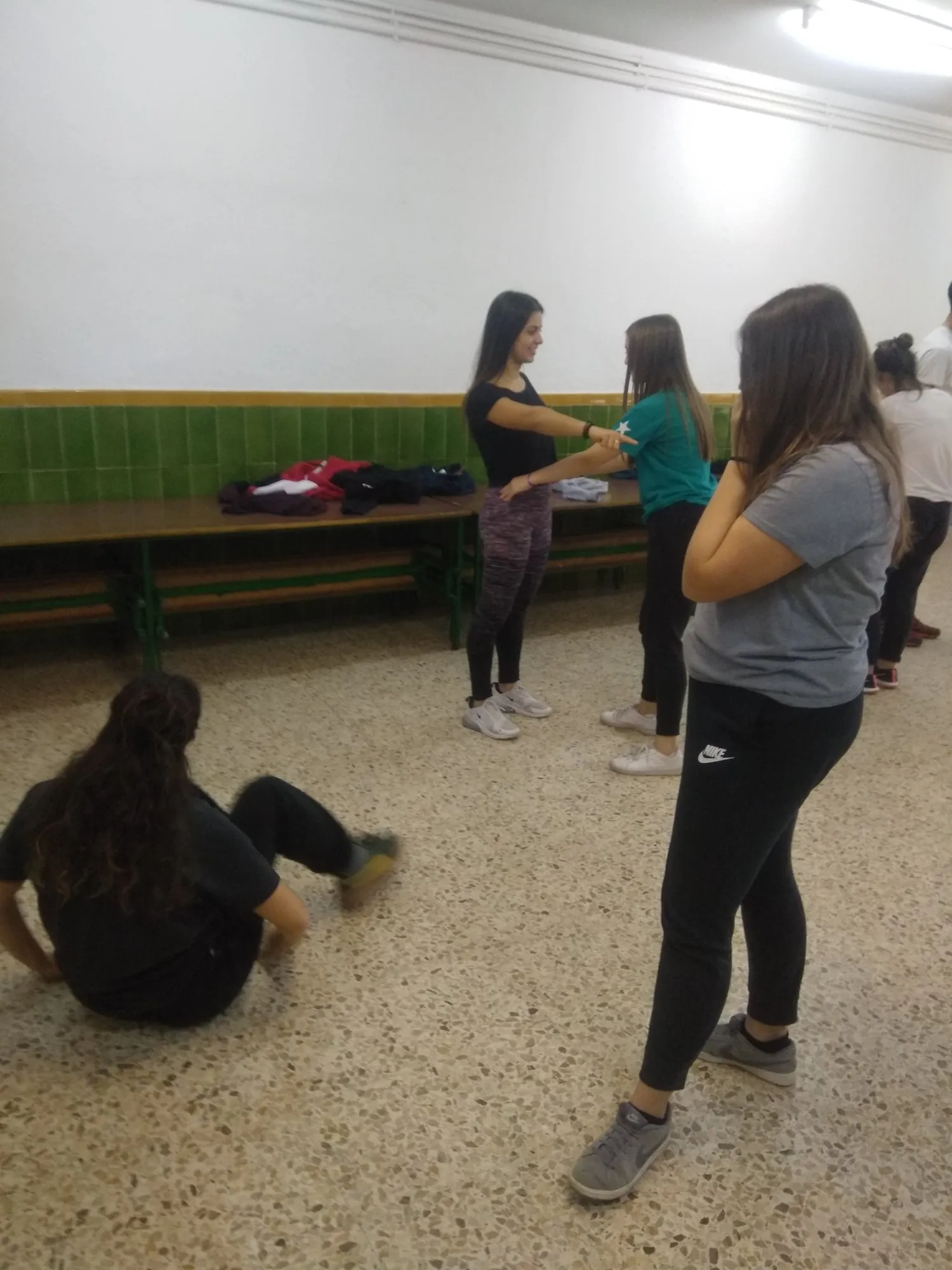 Alumnes fent un exercici de moviment; una d'elles asseguda a terra.