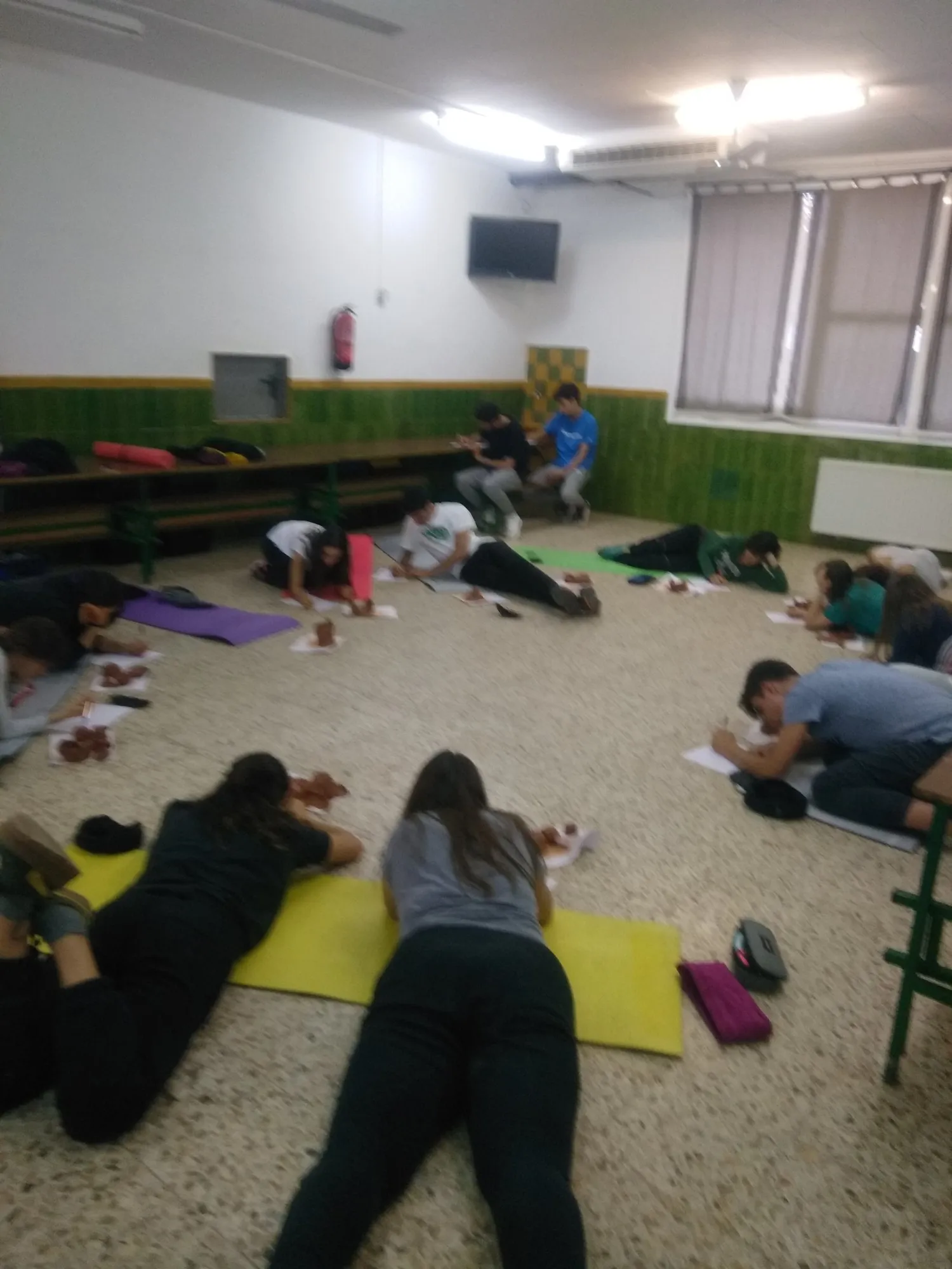 Alumnes estirats sobre màrfegues de colors treballant a terra.