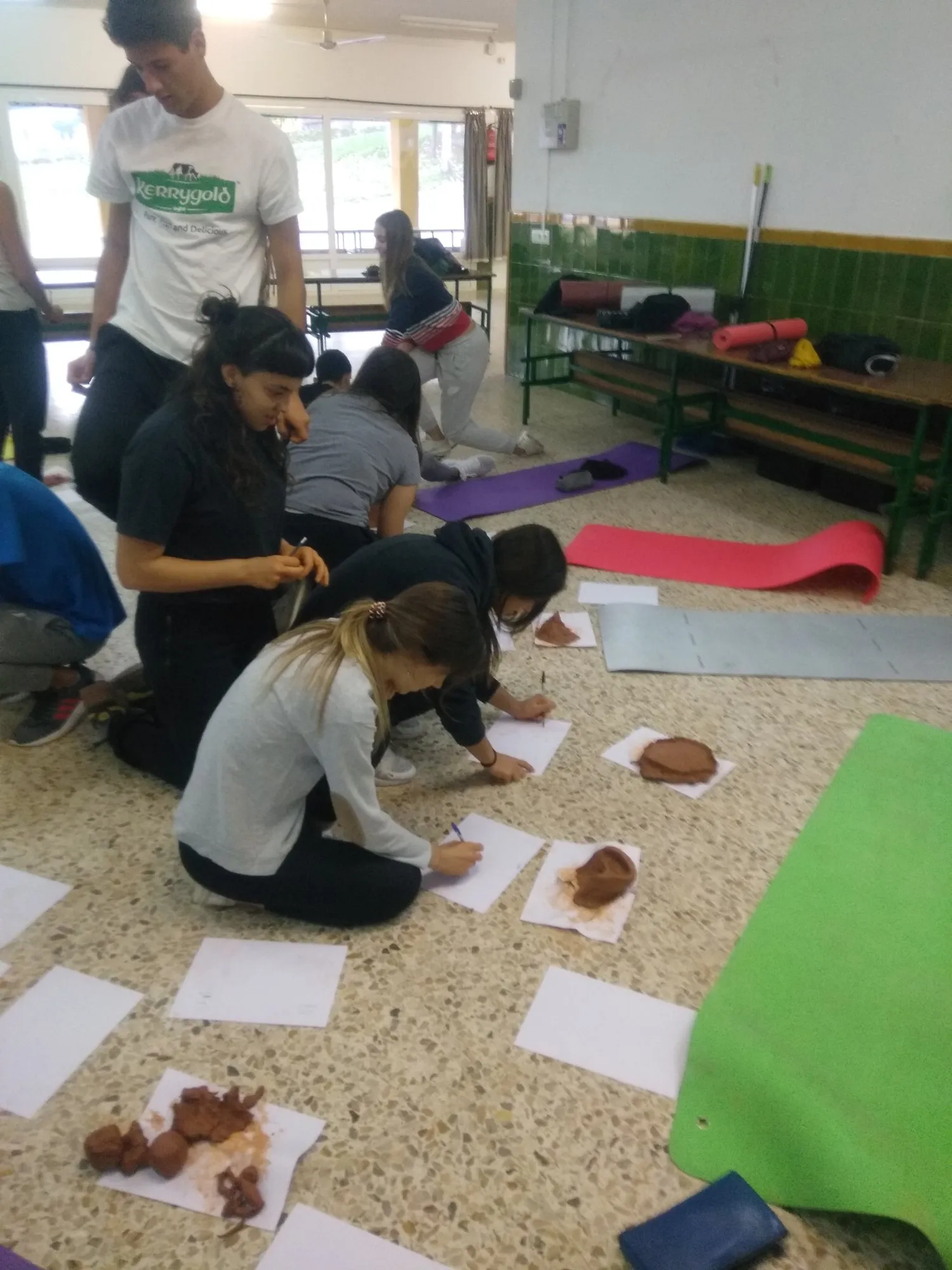 Alumnes concentrades modelant fang sobre màrfegues de colors.