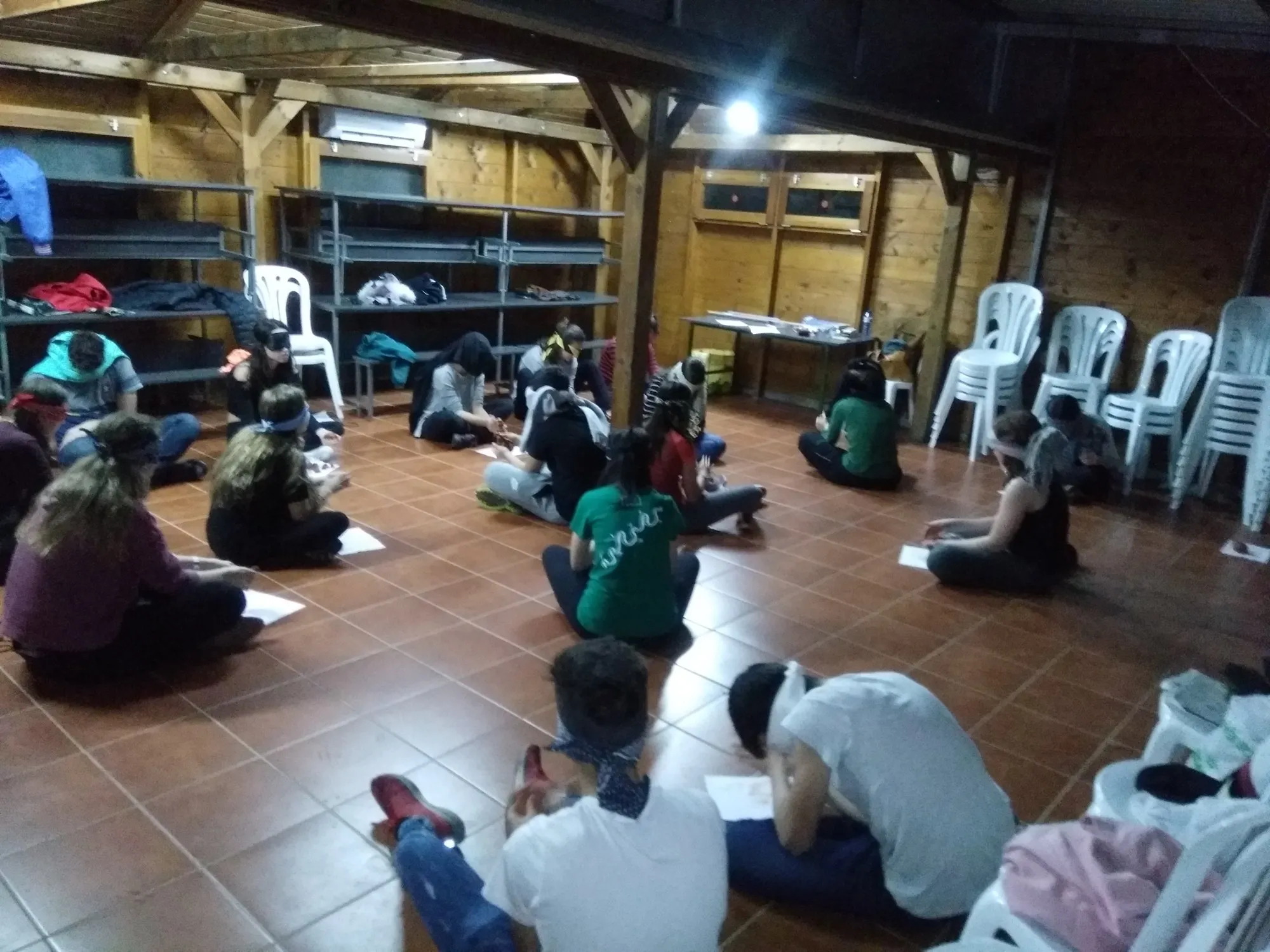 Alumnes asseguts i estirats a terra, cadascú amb el seu full, concentrats en la proposta.