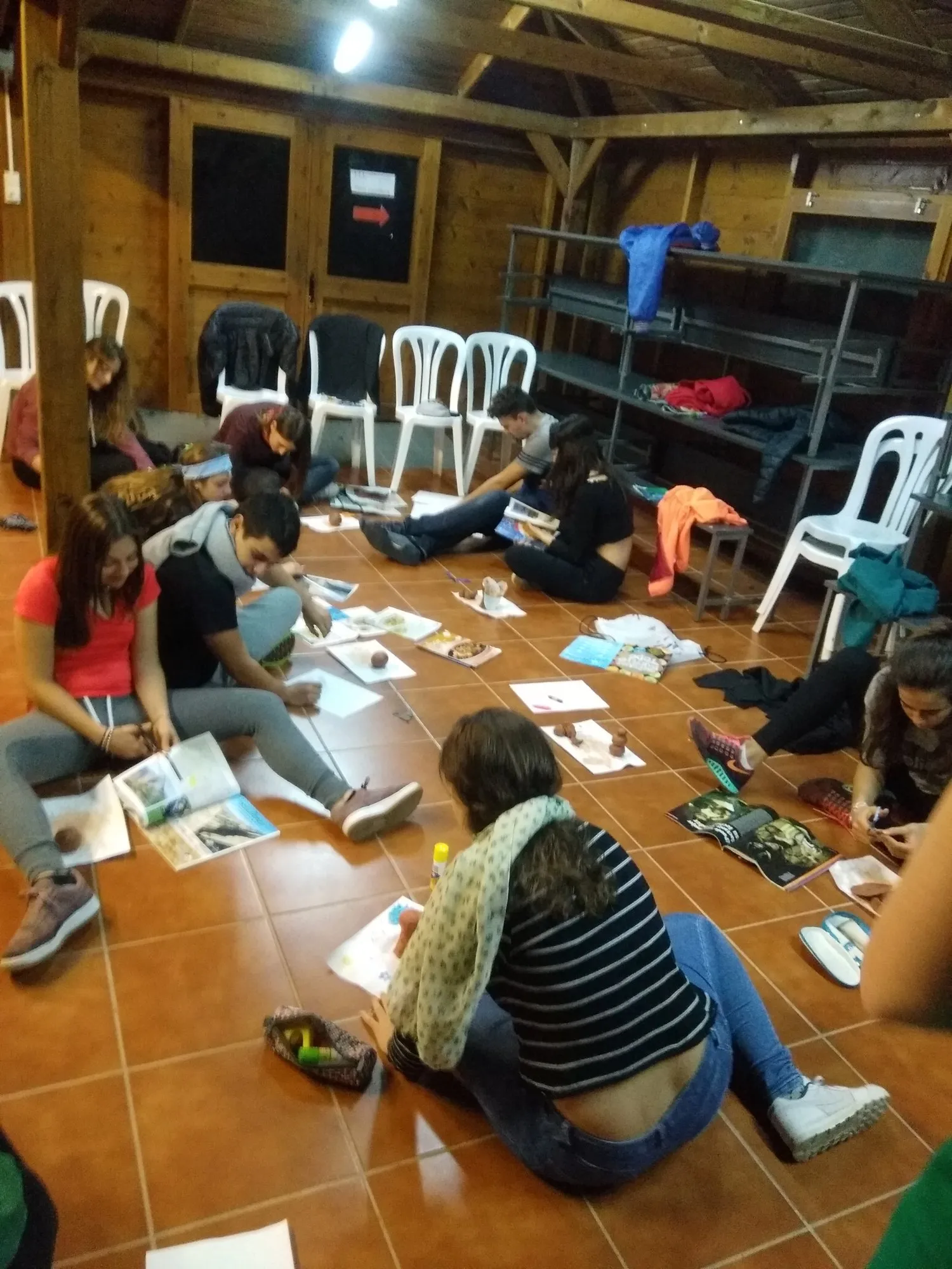 Alumnes treballant a terra amb fulls, retalls i materials diversos.