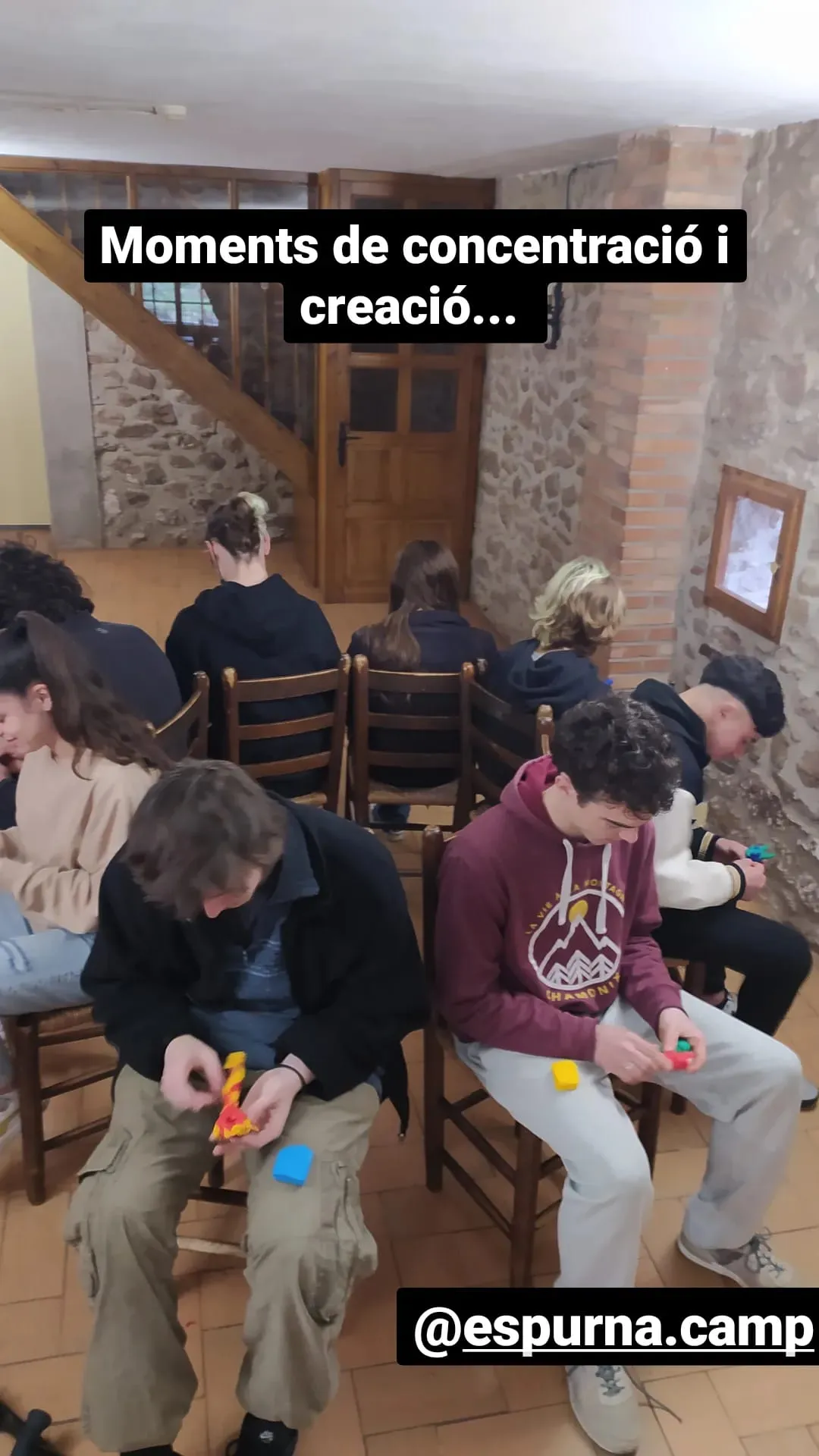 Joves concentrats creant, asseguts en cadires. Text: «Moments de concentració i creació…».